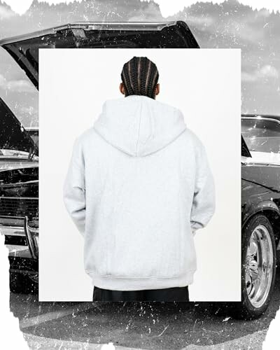 Person with braided hair in a hoodie standing in front of a car with an open hood.
