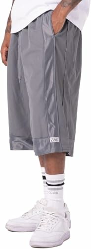 Person wearing gray basketball shorts and white sneakers, showcasing the flexible design and comfort features of the Pro Club Men's Heavyweight Mesh Basketball Shorts.