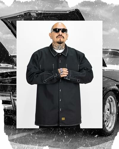 Man in dark jacket and sunglasses standing in front of a car.