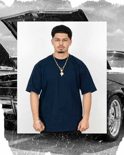 Man in navy t-shirt with gold jewelry stands in front of an open car hood.