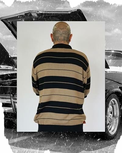 Man in striped sweater standing in front of classic car.