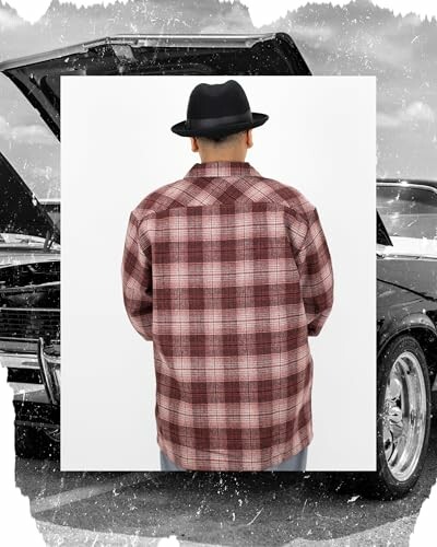 Man in plaid shirt and hat standing in front of a car.