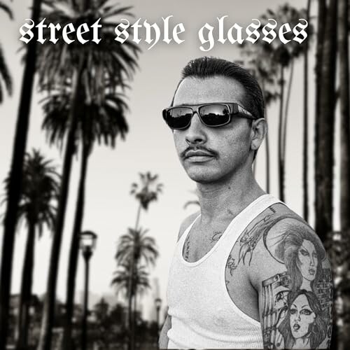 Man with sunglasses and tattoos in a palm tree setting.